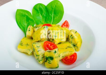 Gnocchi aux épinards avec du beurre fondu et les tomates cerise du jardin Banque D'Images