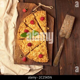 Fabricants de pièces triangulaires de tarte crumble aux pommes sur une planche de bois brun, vue du dessus Banque D'Images