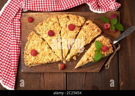 Fabricants de pièces triangulaires de tarte crumble aux pommes sur une planche de bois brun, vue du dessus Banque D'Images