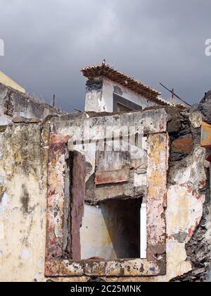 gros plan sur les fenêtres d'une maison abandonnée en chute libre avec un volet brisé et un ciel gris Banque D'Images