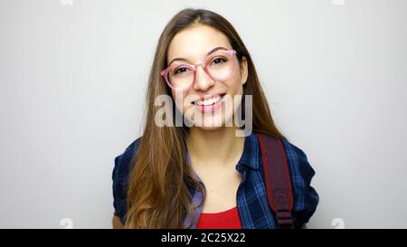 Portrait de jeune fille étudiante positif isolé sur fond blanc portant des lunettes et sac à dos Banque D'Images