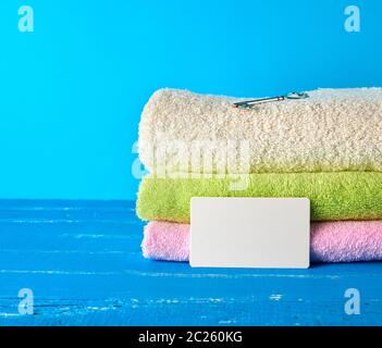 Trois nouveaux multi-couleur terry serviettes pliées sur un fond en bois bleu et les cartes de papier vide. Banque D'Images