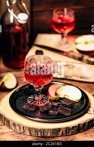 Groseillier rouge maison nalivka et chocolat, avec les tranches de pommes sur le plateau métallique Banque D'Images
