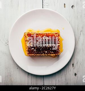 Vue de dessus du délicieux miel délicieux sur la plaque lumineuse de l'éclairage de fond en bois Banque D'Images