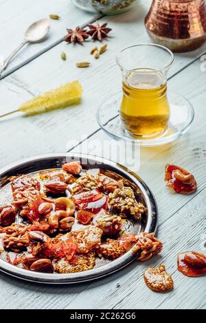Oriemtal se régale de noix et de graines sur plaque métallique avec tisane en verre armudu sur une surface en bois clair Banque D'Images