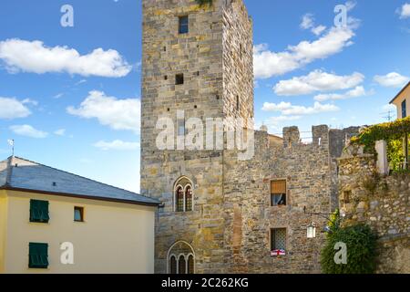 Une italienne s'incline de sa fenêtre d'appartement dans une tour médiévale le long des anciens murs de la ville de Portovenere, en Italie Banque D'Images