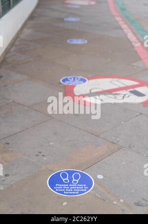 LONDRES, ANGLETERRE - 6 JUIN 2020 : autocollants de distance circulaire sur le sol indiquant les exigences physiques de distance pour une file d'attente à l'extérieur de Moorfiel Banque D'Images