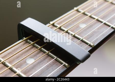 Capo noir sur la chaîne Guitare acoustique et une touche de fonction avec lumière naturelle en vue rapprochée Banque D'Images