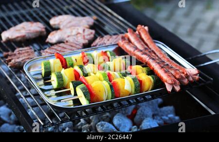 Brochettes de légumes, saucisses et steak sur le gril Banque D'Images