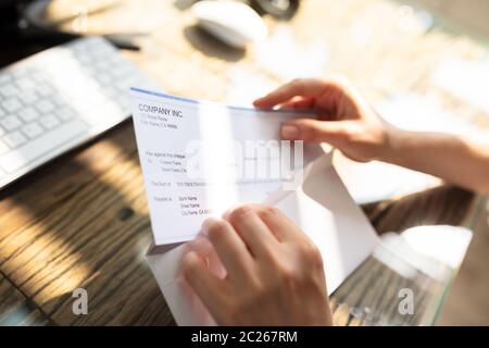 Close-up de l'homme d'affaires d'ouverture de l'enveloppe avec un chèque en bois de plus de 24 Banque D'Images