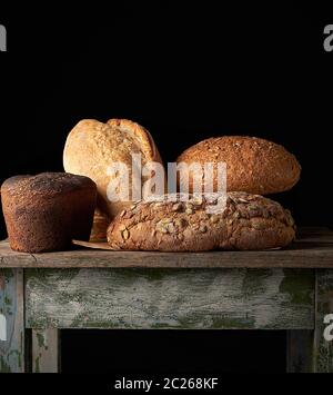 Ensemble de divers petits pains de seigle cuit sur une vieille table en bois, fond noir Banque D'Images