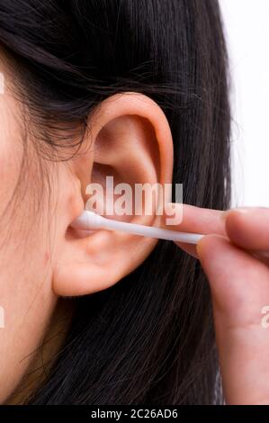 Femme avec de longs cheveux noirs est le nettoyage de ses oreilles avec le blanc coton-tige. Concept d'hygiène personnelle. Banque D'Images