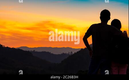 Vue arrière du couple romantique magnifique coucher de soleil sur la couche de montagne. Voyage couple. Backpacker heureux dans l'amour et les voyages de noces. Silhouet Banque D'Images