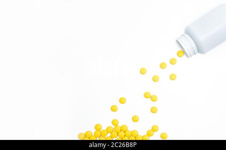 Les comprimés pelliculés jaune pills spilling out de bouteille de pilules sur fond blanc avec l'exemplaire de l'espace. Comprimés comprimé analgésique. Ains comprimés pour la pai Banque D'Images