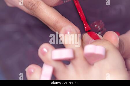 Femme qui reçoit un service de pédicure ongle Pédicure Manucure à par. L'application de gel esthéticienne rouge couleur de l'ongle du client à clou et spa salon. Foo Banque D'Images