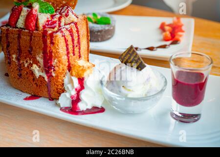 Toast au miel avec garniture fraises, un côté de la crème fouettée, crème glacée à la vanille. Toast de pain sur un plat blanc sur fond flou de lave de chocolat c Banque D'Images