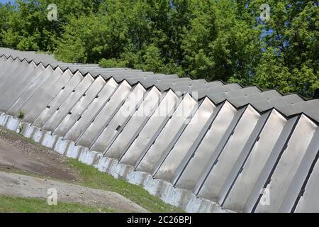 Hangar industriel avec murs en aluminium et supports de toit sur une fondation en béton près des arbres verts Banque D'Images