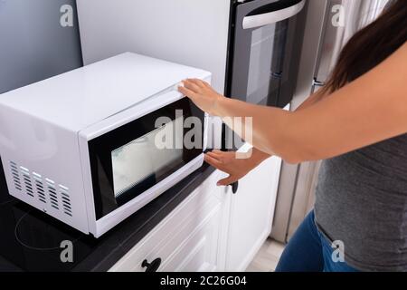 Close-up of a Woman appuyant sur le bouton d'un four micro-ondes Banque D'Images