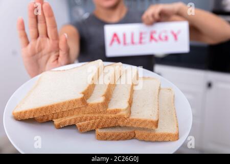 Jeune femme refusant tranche de pain sur la plaque à la carte texte Allergie Holding Banque D'Images