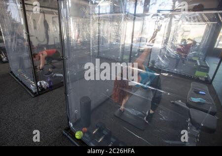 Los Angeles, Californie, États-Unis. 16 juin 2020. Les gens s'exercent à inspire South Bay Fitness derrière des feuilles de plastique dans leurs boîtiers d'entraînement tout en observant la distance sociale le 16 juin 2020 à Redondo Beach, Californie, alors que la salle de gym rouvre en vertu des directives de réouverture de la phase 3 du coronavirus de Californie. Crédit : Ringo Chiu/ZUMA Wire/Alay Live News Banque D'Images