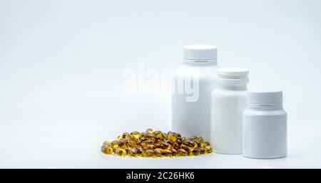 Capsules de gélatine douce jaune avec flacon en plastique blanc sur fond blanc avec étiquette vierge et espace de copie. Vitamine et supplément concept. Pharm Banque D'Images