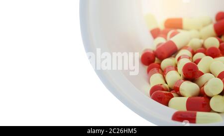 Capsules rouges et jaunes dans un récipient ouvert en plastique blanc. Concept de santé mondiale. Résistance aux antibiotiques. Capsule antimicrobienne p Banque D'Images