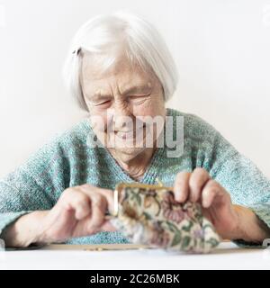 Personnes âgées gaies 96 ans woman sitting at table à la maison heureux avec elle dans son portefeuille d'épargne-retraite après le paiement des factures. L'épargne-retraite un Banque D'Images