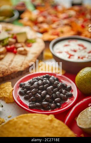 Gros plan sur les haricots noirs avec divers aliments mexicains fraîchement préparés Banque D'Images