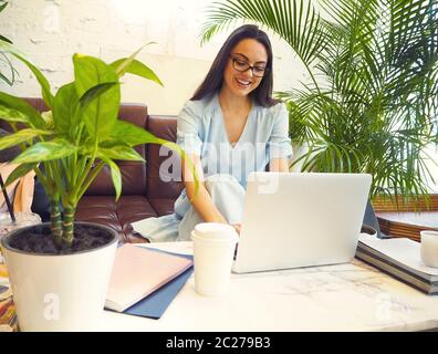 Belle femme de course mixte assise dans un café avec son ordinateur portable Banque D'Images