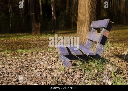 Banc solitaire sous les arbres et avec les feuilles tombées en automne Banque D'Images