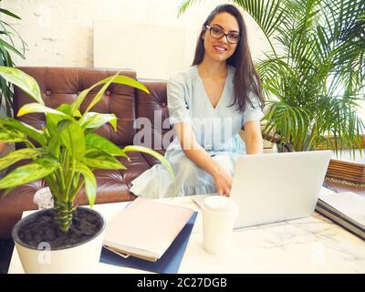 Belle femme de course mixte assise dans un café avec son ordinateur portable Banque D'Images