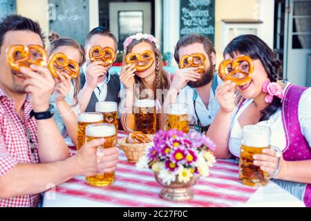 Groupe dans le jardin bavarois de bière en regardant à travers les trous de bretzel à la caméra Banque D'Images