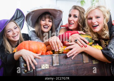 Portrait de quatre jeunes et belles femmes portant des costumes de sorcière tout en posant avec des citrouilles et un vieux tronc à Halloween Banque D'Images