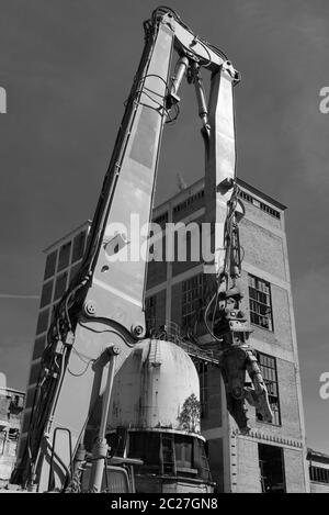 Pinces de démolition sur une pelle mécanique sur un chantier en noir et blanc Banque D'Images