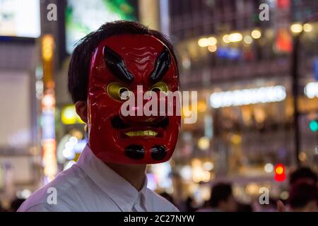 Un jeune Japonais porte un masque de Tengu lorsqu'il interroge les gens pour une vidéo youtube sur la place Hachiko, Shibuya, Tokyo, Japon. Banque D'Images