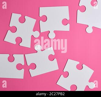 Grand blanc puzzles en blanc sur un fond rose, vue du dessus Banque D'Images
