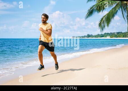 Jeune homme courant sur la rive de la plage tropicale Banque D'Images