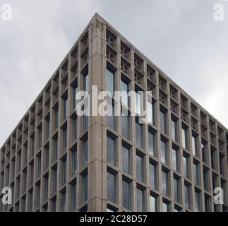 un coin de détail d'un immeuble de bureaux en béton typique de style brutaliste des années 1960 avec cadre en béton géométrique contre un cloo gris Banque D'Images