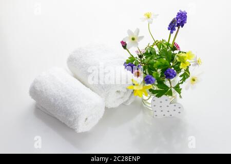 Serviettes à côté d'un pot crème devant un fond blanc et fleurs dans un vase. Banque D'Images