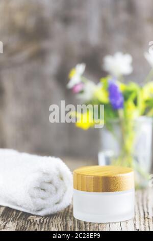 Serviettes à côté d'un pot crème devant un fond blanc et fleurs dans un vase. Banque D'Images