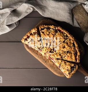 La moitié crumble Tarte aux prunes sur une planche à découper en bois brun, vue du dessus Banque D'Images