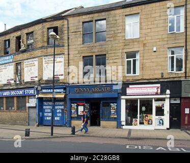 deux personnes se promontdevant un magasin de produits abandonnés et une salle d'arcade sur la place oastler dans le west yorkshire de bradford Banque D'Images