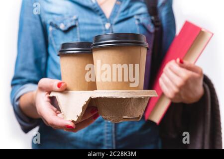 Papier pour faire deux tasses de café dans la main de la femme. Étudiant avec les tasses de café à emporter et livre dans ses mains Banque D'Images