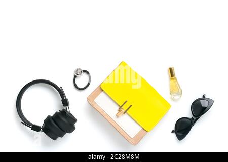 Accessoires pour femmes Sac à main jaune, beige, casque sans fil, parfum, croquant, lunettes de soleil noires isolées sur fond blanc vue du dessus Flat Lay Banque D'Images