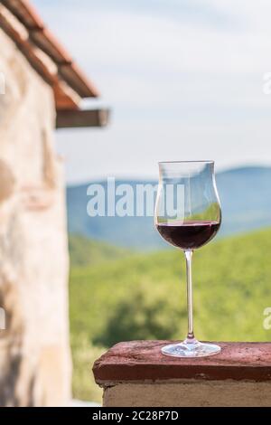 Verre de vin rouge en Toscane. Vignobles en arrière-plan. Banque D'Images