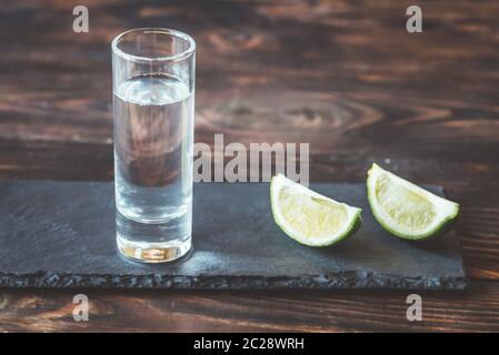 Verre de tequila avec tranches de lime sur le bord en pierre Banque D'Images