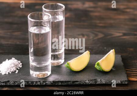 Verres de tequila avec tranches de lime sur le bord en pierre Banque D'Images