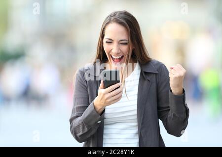 Vue avant portrait de femme excité à la ligne de téléphone intelligent contrôle contenu dans la rue Banque D'Images