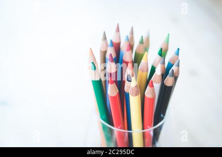 Créativité: Crayons de couleur dans une boîte sur table rustique en bois, fond blanc Banque D'Images