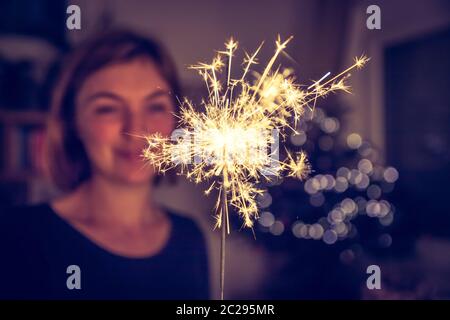 Une fille heureuse tient un sparkler à l'heure de Noël Banque D'Images